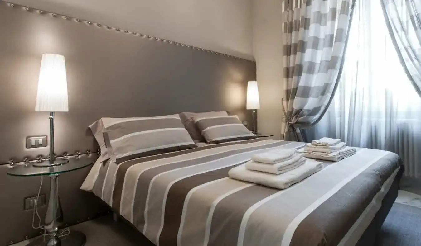 Een tweepersoonsbed in een hotelkamer ingericht in minimalistische stijl met verschillende grijstinten bij Brera Prestige B&B, een hotel in Milaan, Italië