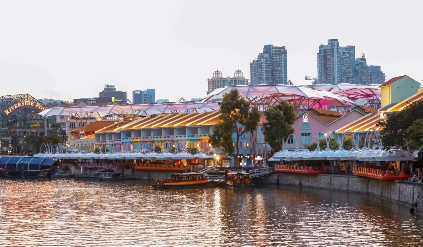 Singapur'da Clarke Quay'den geçen teknelerin olduğu bir akşam sahnesi