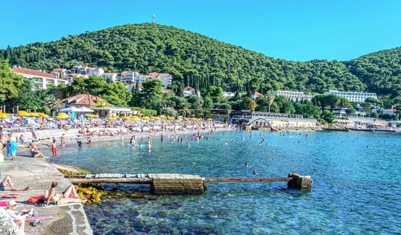 Ljudje, ki poležavajo na plaži Lapad na sončen dan v Dubrovniku na Hrvaškem