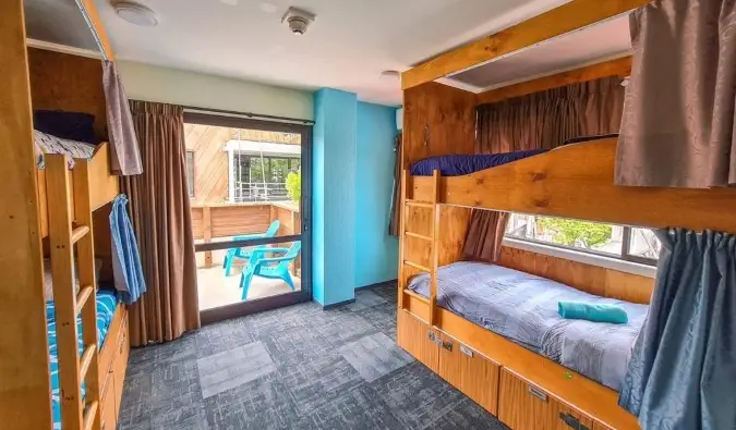 Giường tầng bằng gỗ có rèm riêng tư trong căn phòng tràn ngập ánh sáng tại Adventure Queenstown Hostel ở Queenstown, New Zealand