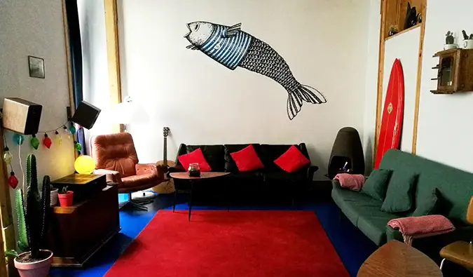 Espace commun avec un mélange de canapés et un gros poisson peint sur le mur du Goodnight Hostel, Lisbonne