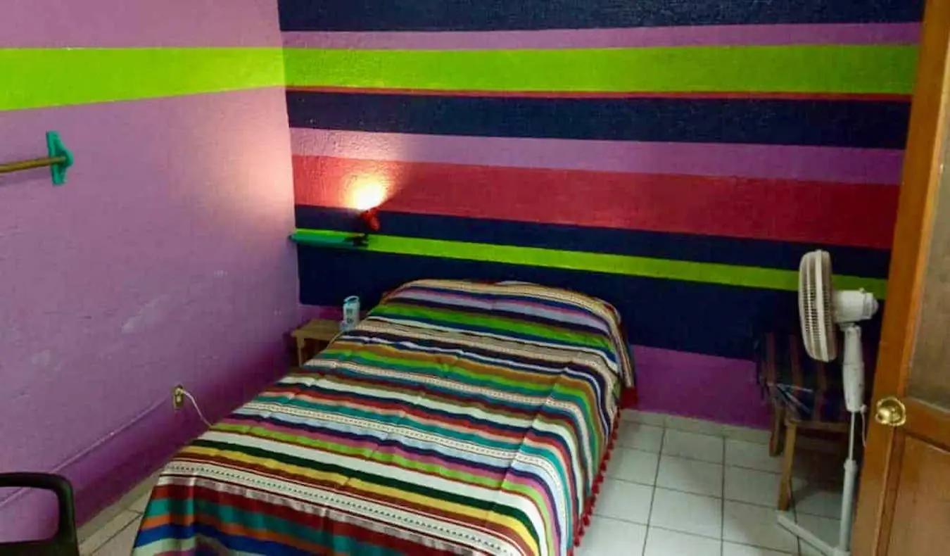 En färgglad enkelsäng på det budgetvänliga Iguana Hostel i Oaxaca, Mexiko