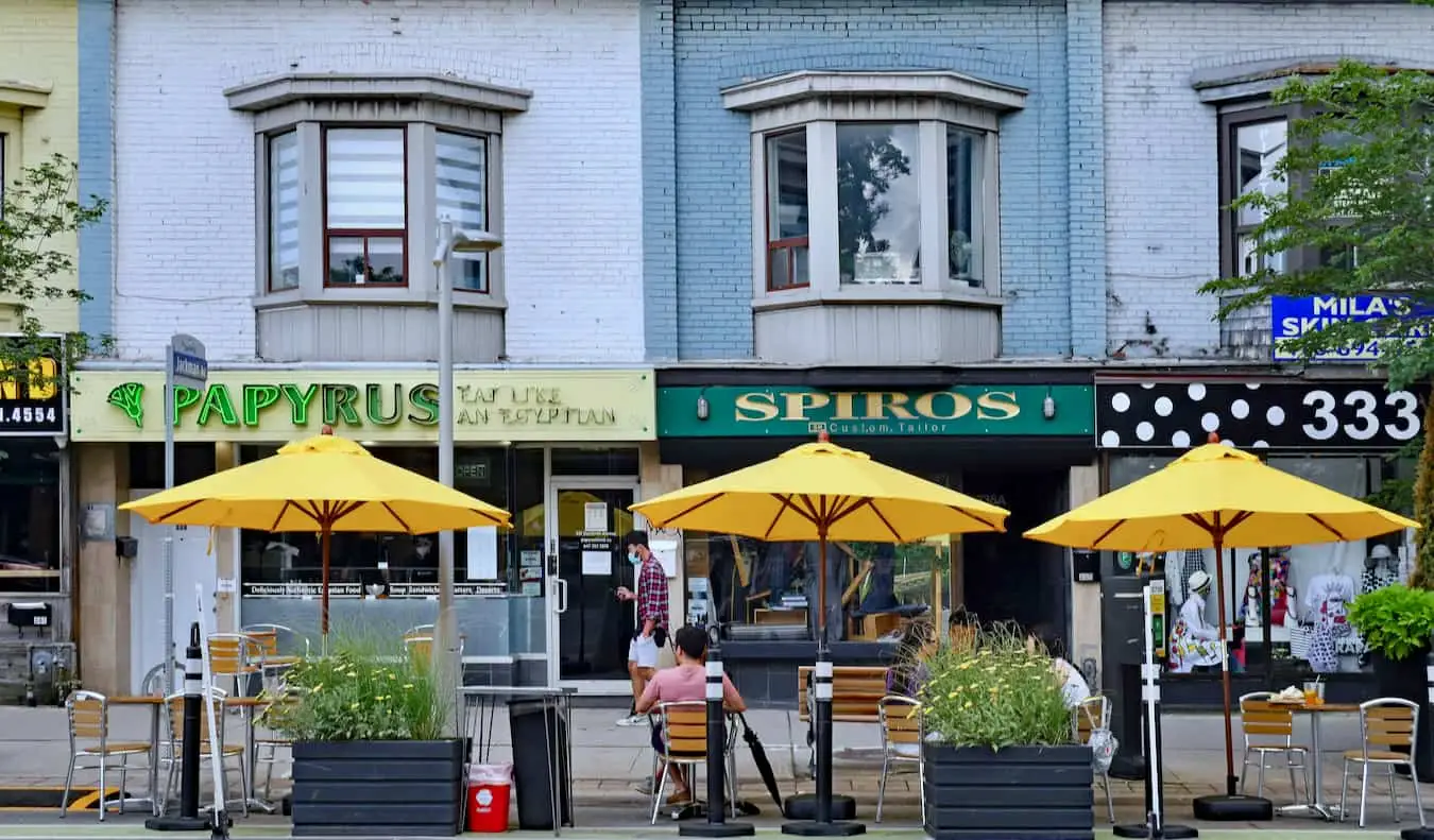 Oameni care se relaxează la un restaurant afară, în zona Danforth din Toronto, Canada