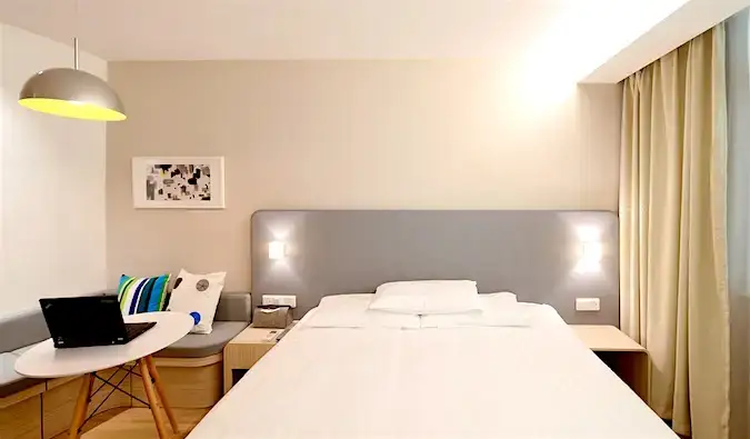 Cama, escritorio y sofá en una habitación de hotel.