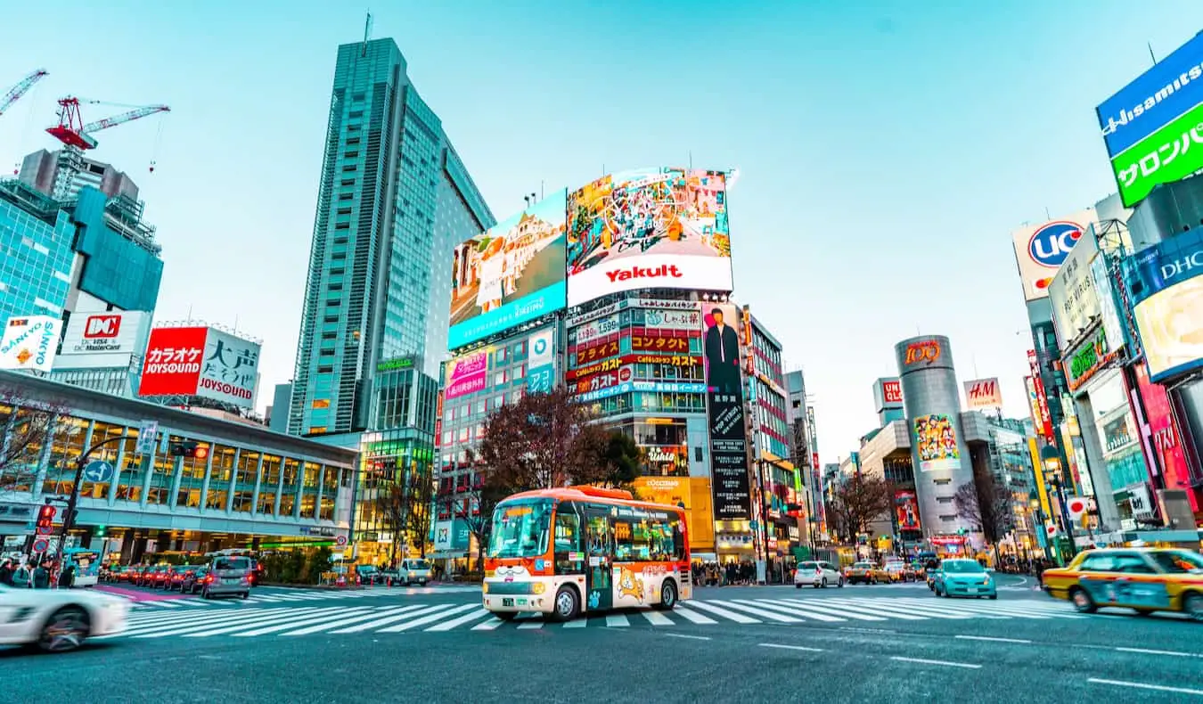 Folk som krysser gaten under travel trafikk rundt Shibuya-området i Tokyo, Japan