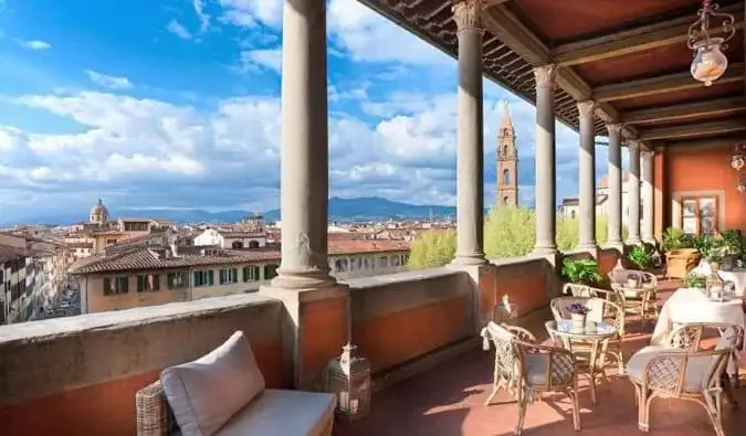 Um terraço na cobertura com cadeiras e mesas com vista para a paisagem urbana de Florença, Itália, no Hotel Palazzo Guadagni