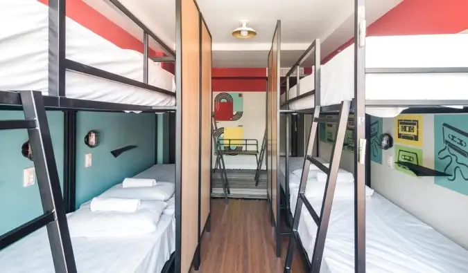 Mga metal na bunk bed sa isang dorm room na may makulay na pader sa Selina Lapa hostel sa Rio de Janeiro, Brazil