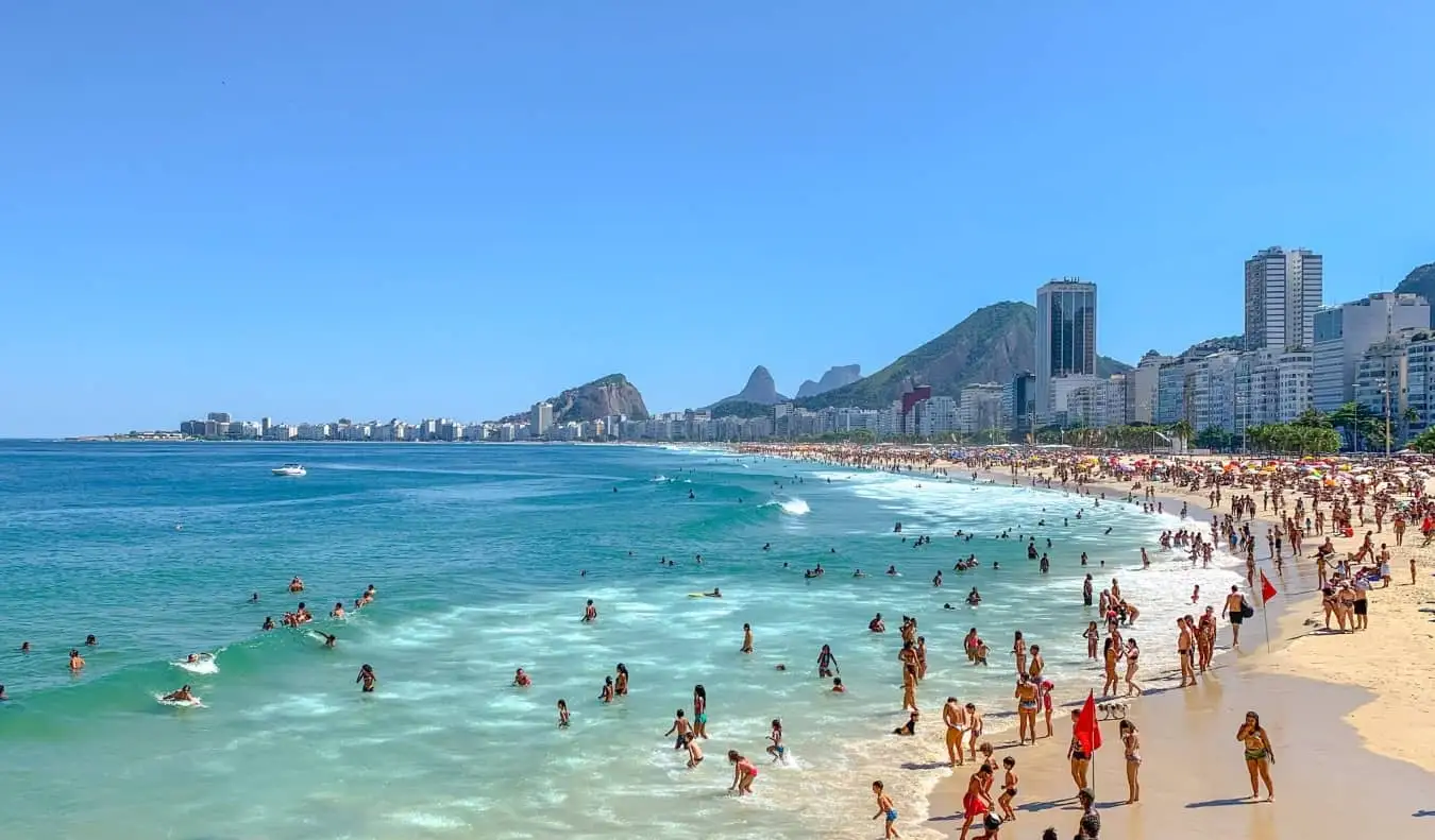 Žmonės, besilinksminantys vandenyne palei ilgą paplūdimio ruožą, apsuptą daugiaaukščių pastatų Rio de Žaneire, Brazilijoje