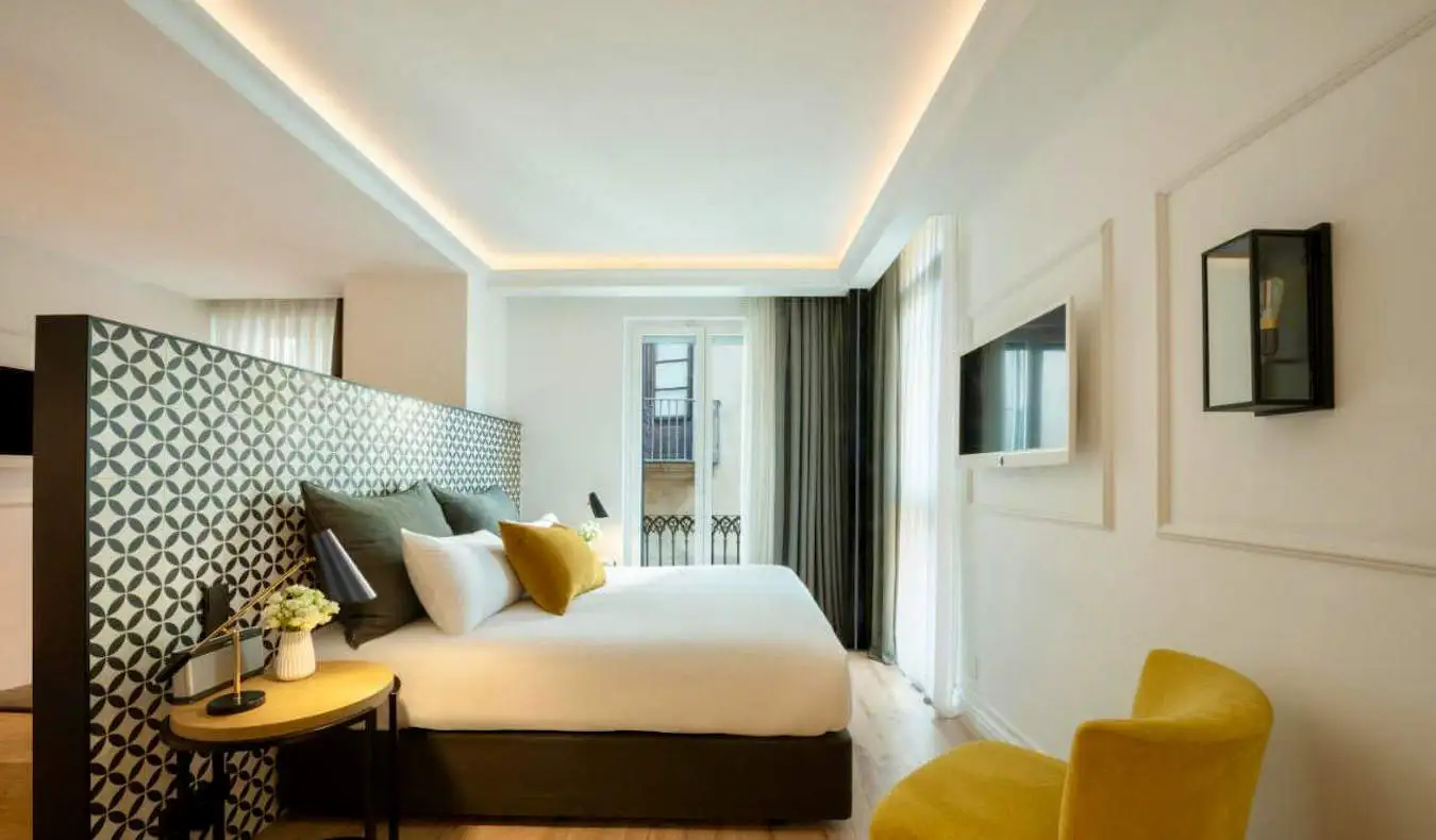 Tempat tidur besar di kamar hotel yang nyaman di Serras di Barcelona, ​​Spanyol