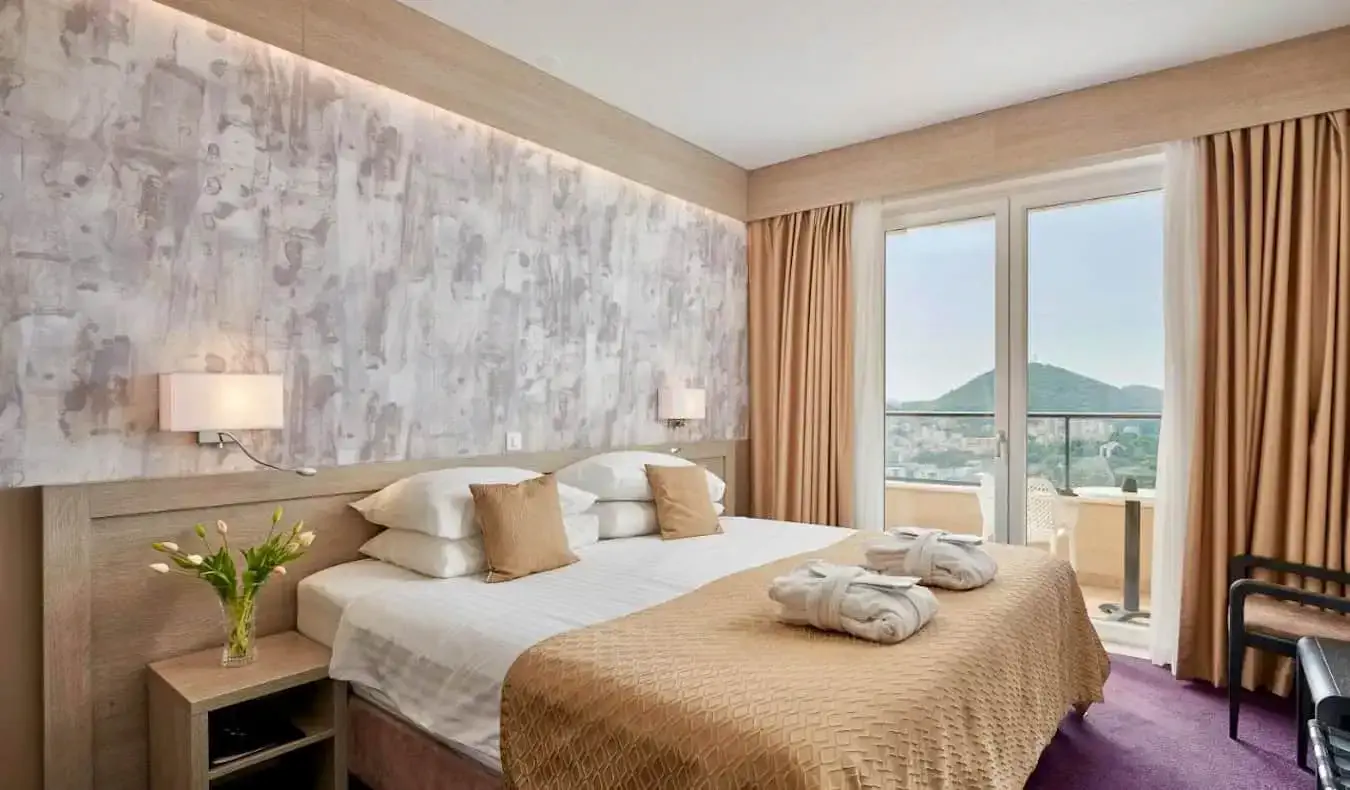 Tempat tidur besar dan nyaman di kamar hotel besar di Hotel Adria di Dubrovnik, Kroasia