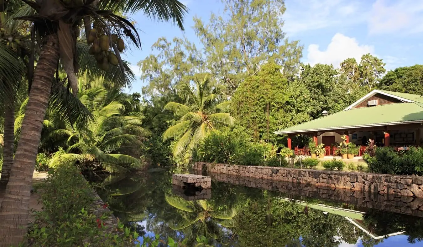 Pension met uitzicht op een rustig kanaal omgeven door een dicht bos met palmbomen op de Seychellen