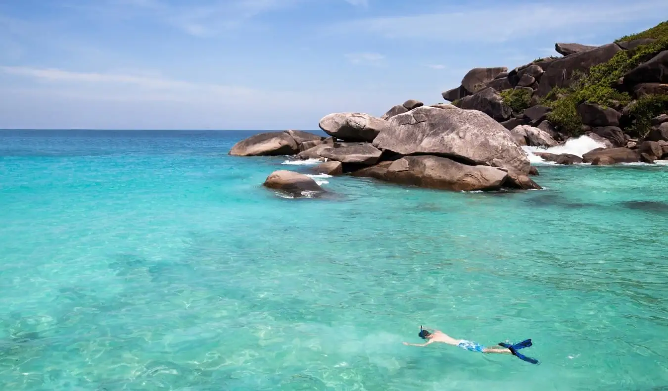 Muž šnorchluje v křišťálově čistých vodách na Seychelách