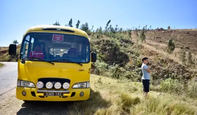 Matt stojící vedle žlutého autobusu na kraji silnice