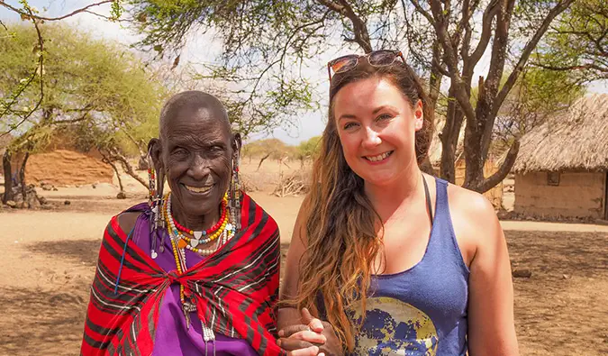 Eine alleinreisende Frau posiert mit einem Einheimischen während ihrer Freiwilligenarbeit in Afrika