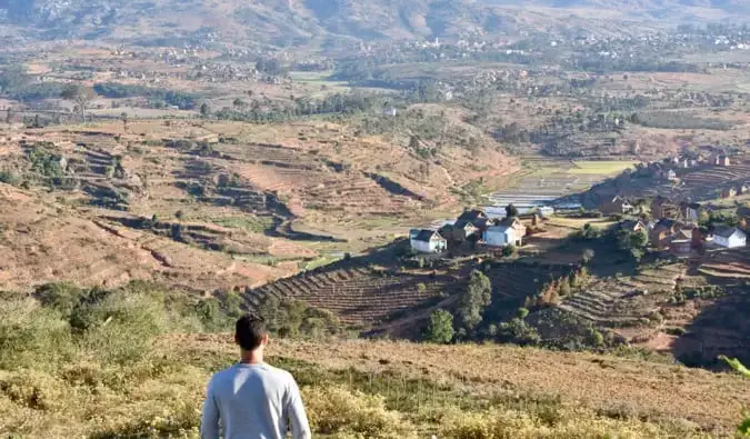 Il nomade Matt in piedi in un'arida valle piena di campi marroni nel Madagascar