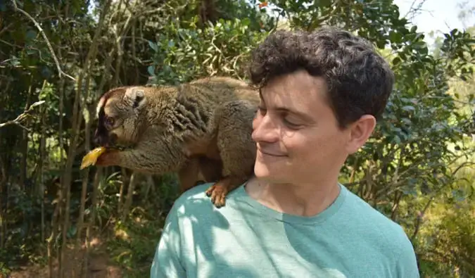 Nomaden Matt dengan lemur coklat duduk di bahunya di Madagaskar