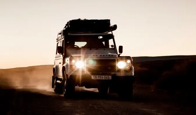 Isang safari tour jeep na nagmamaneho sa isang maalikabok na kalsada sa Africa