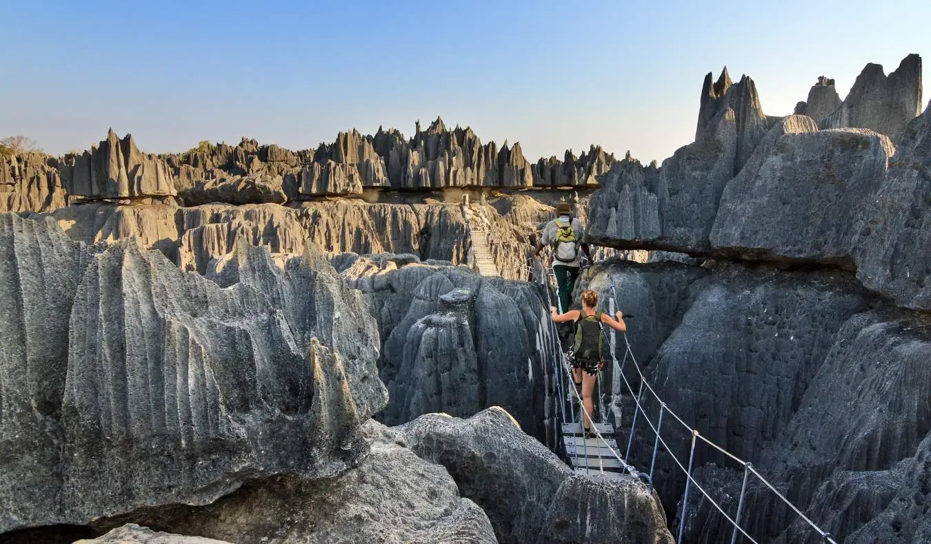 Oameni care merg pe un pod de frânghie în apropierea unui defileu imens de lângă Tsingy în Madagascar