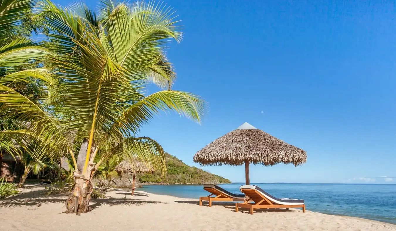 Een wit zandstrand met ligstoelen erop in Nosy Be, Madagaskar