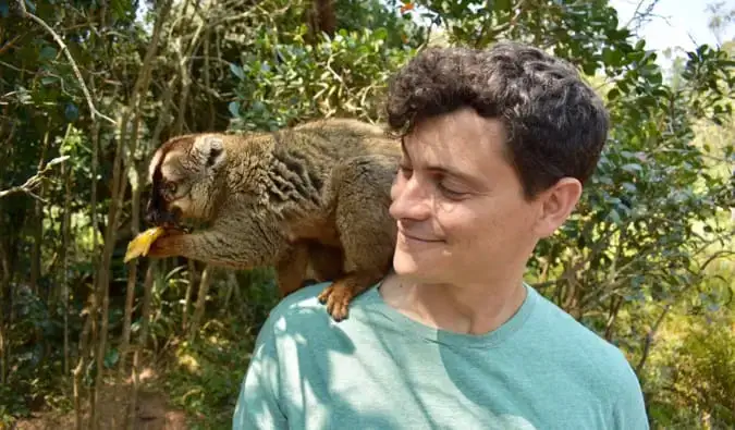 Il nomade Matt posa con un lemure sull'isola dei lemuri in Madagascar