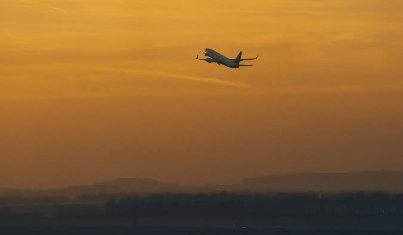 Ein Flugzeug, das während eines leuchtend orangefarbenen Sonnenuntergangs startet