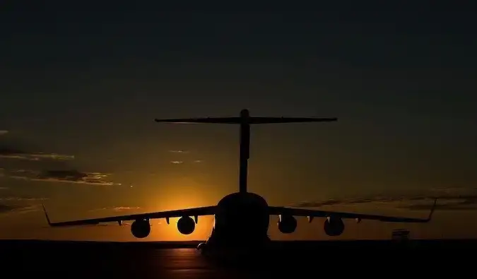 Um avião escuro e obscurecido em um aeroporto durante um pôr do sol brilhante