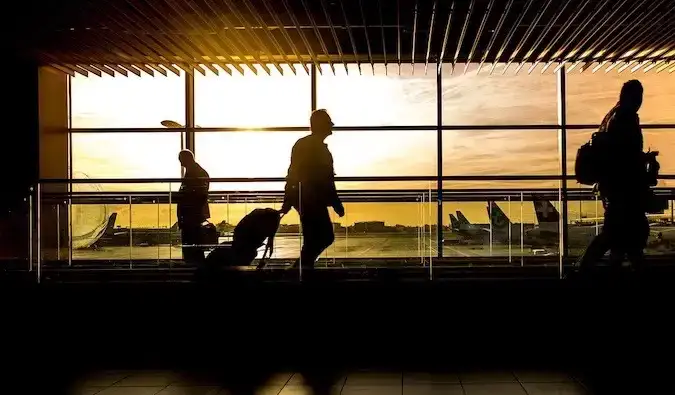 Een man die door een luchthaven loopt en zijn bagage trekt