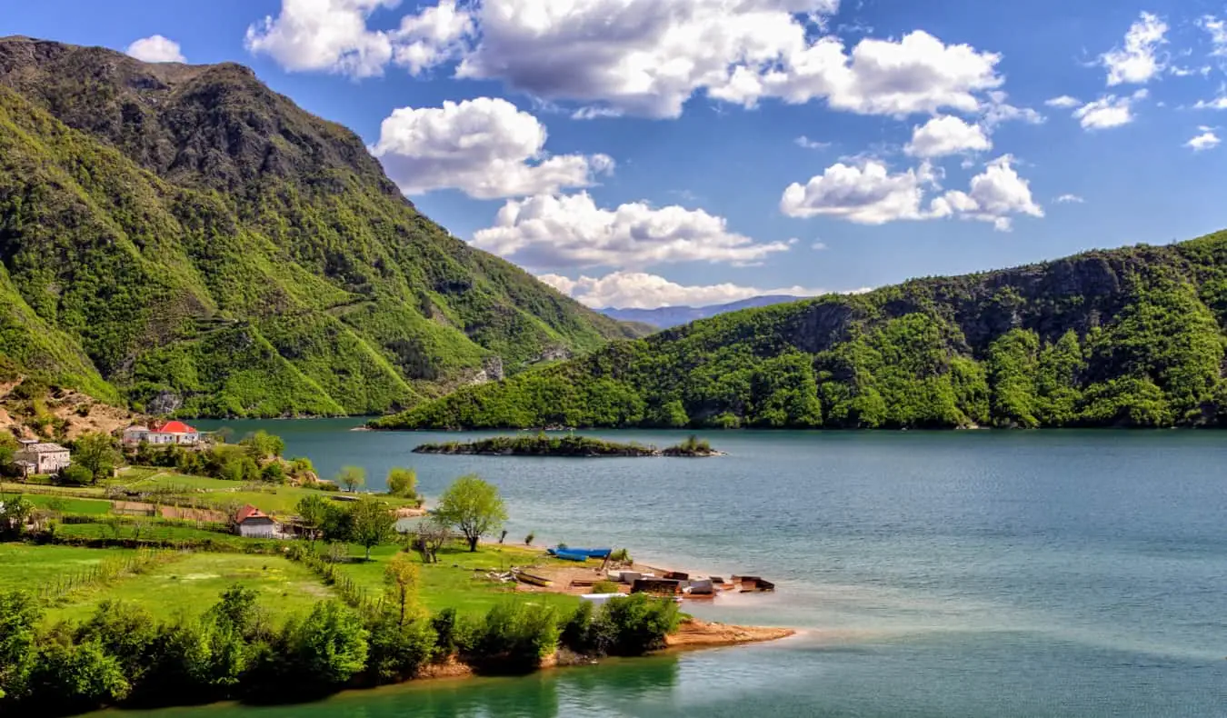 Isang tahimik na lawa na napapalibutan ng mayayabong na halaman sa Albania