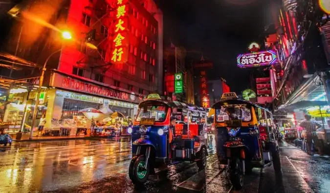 Ảnh chụp cận cảnh những chiếc xe tuk-tuk ở Bangkok, được bao quanh bởi ánh đèn neon rực rỡ vào ban đêm