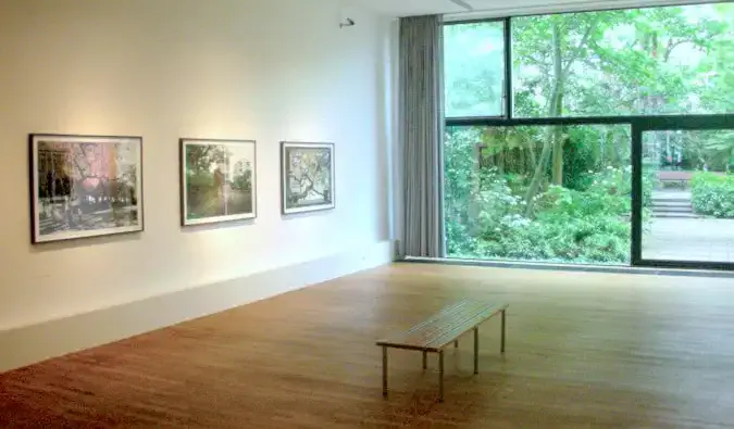 Sala de galerie minimală cu fotografii înrămate pe perete și o bancă pe care să stai la muzeul de fotografie FOAM din Amsterdam