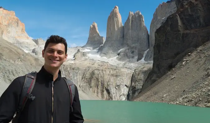 Nomaden Matt poserar för ett foto i Torres del Paine med höga berg i bakgrunden