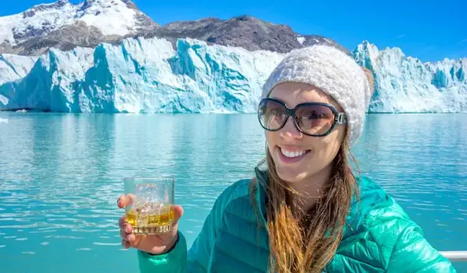 Vrouwelijke soloreiziger Kristin Addis poseert met een drankje bij de O’Higgins-gletsjer in Patagonië