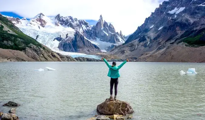 Nakatayo si Kristin Addis sa isang bato sa tubig ng Cerro Torre sa Patagonia