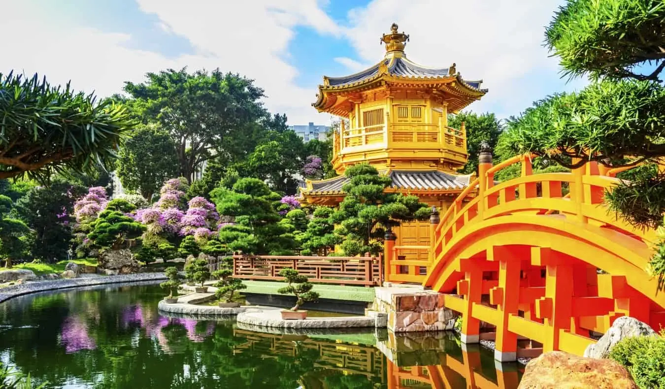 zelta pagoda ar tiltu, kas iet pāri atstarojošam baseinam Nan Lian dārzā Kowloon parkā, Honkongā