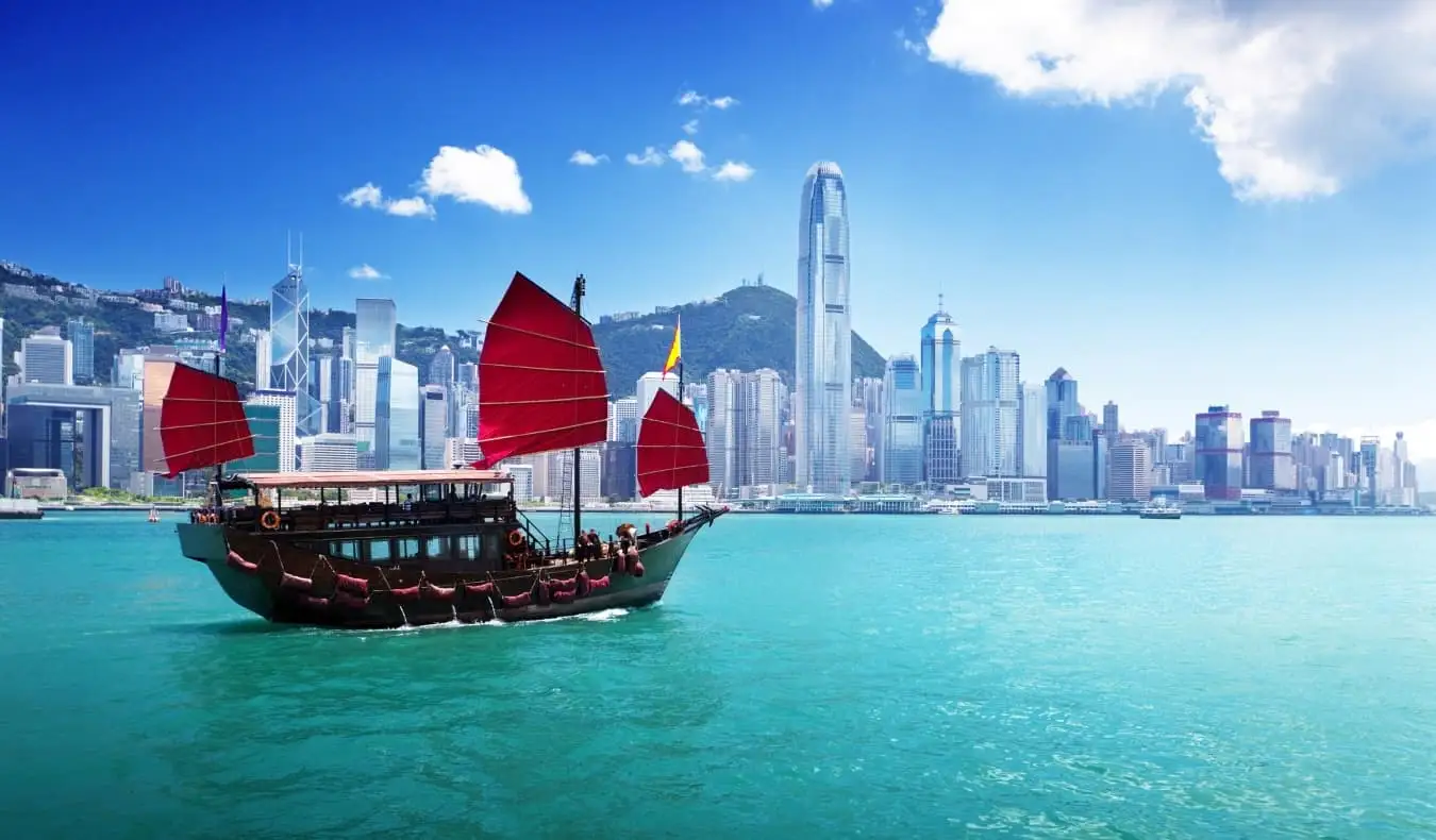 Een jonkboot met zijn kenmerkende rode zeilen in de haven van Hong Kong