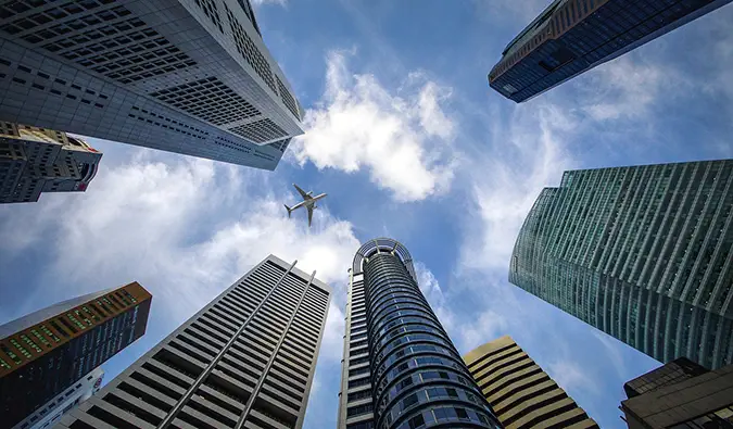 een opwaarts zicht van een vliegtuig tussen wolkenkrabbers in Singapore