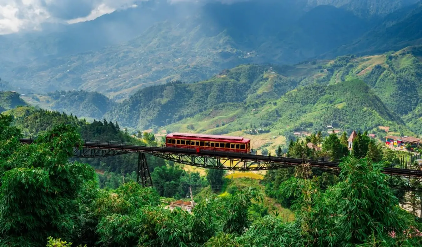 Pemandangan pegunungan yang indah, hijau, dengan perlintasan kereta api di jembatan kereta api yang ditinggikan di Vietnam