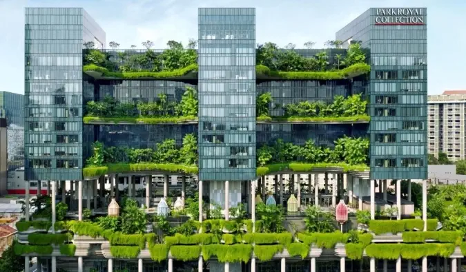 Ydersiden af ​​PARKROYAL COLLECTION Pickering, et 5-stjernet hotel i Singapore, dækket af frodige planter, der flyder ned fra balkonerne