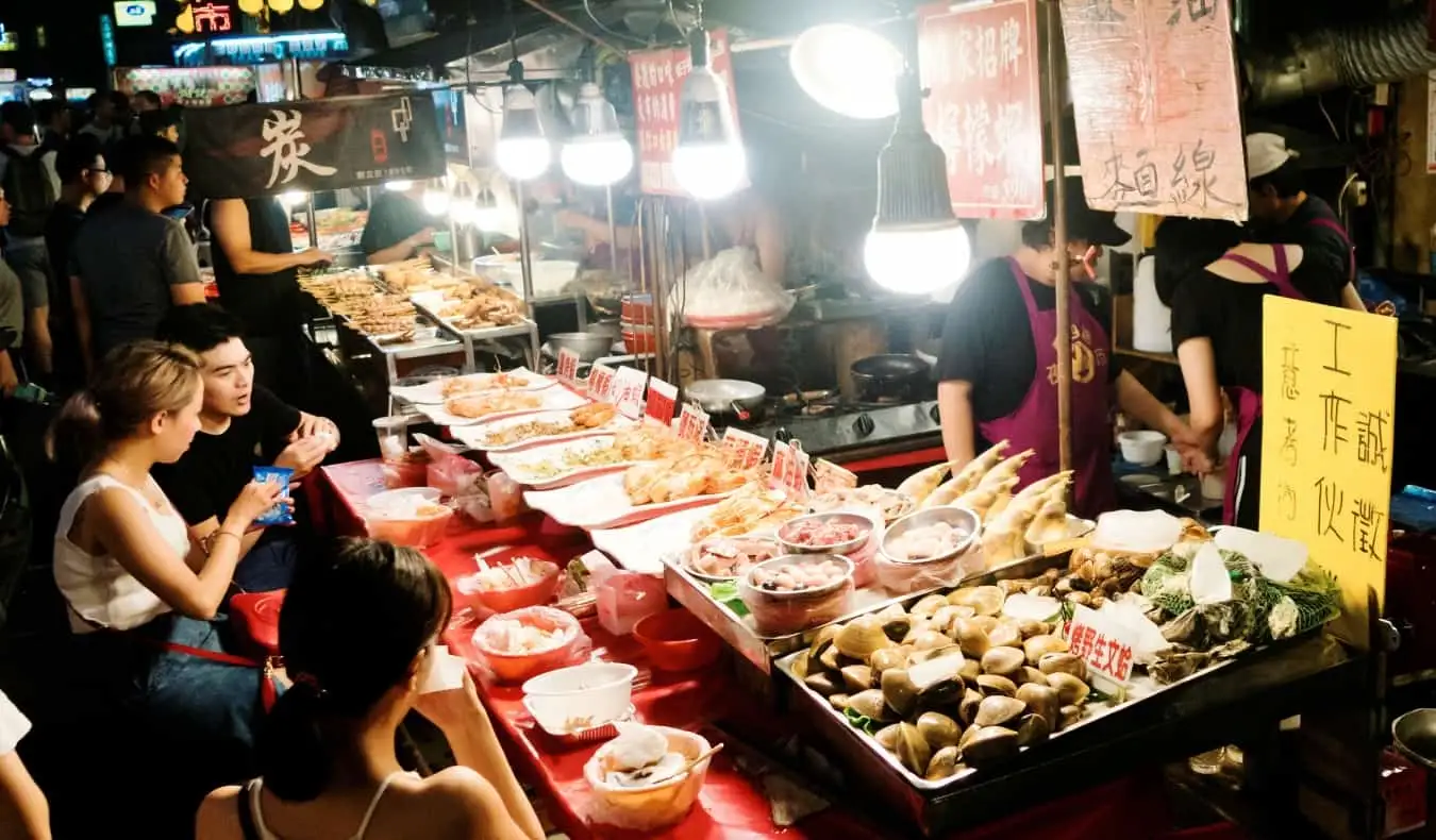 Orang-orang makan di warung pinggir jalan di Pasar Malam Keelung di Taiwan