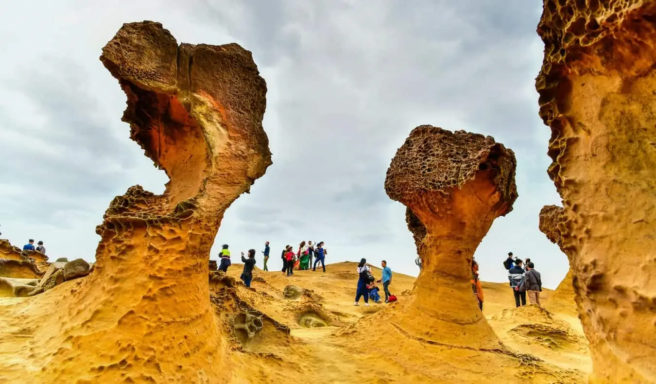 Menschen, die um riesige, sandsteinfarbene Felsformationen im Yehliu Geopark, Taiwan, spazieren