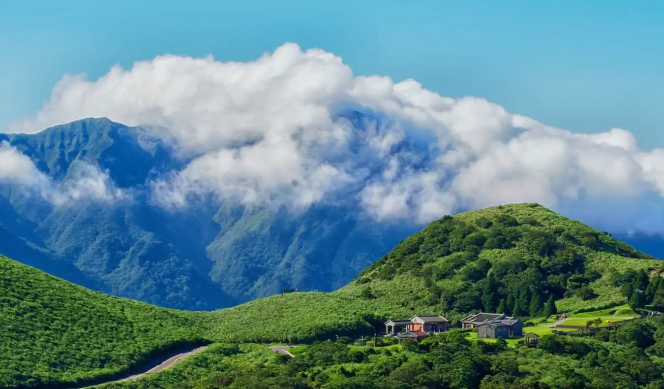 Montagne verdi coperte di nuvole con un piccolo villaggio in primo piano a Taiwan