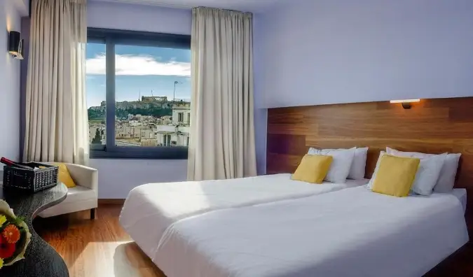 ห้องพักที่ Athens Center Square Hotel ซึ่งมีหน้าต่างเปิดให้เห็น Acropolis ในระยะไกล