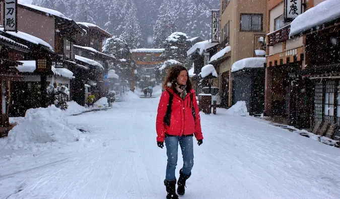 Eine alleinreisende Frau, die im Winter auf einer verschneiten Straße in Japan spaziert