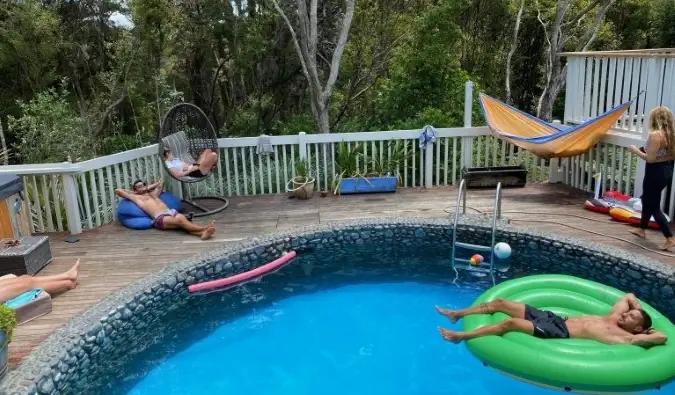 Pessoas relaxando dentro e ao redor de uma piscina externa no albergue Hekerua Lodge Backpackers, na Ilha Waiheke, na Nova Zelândia