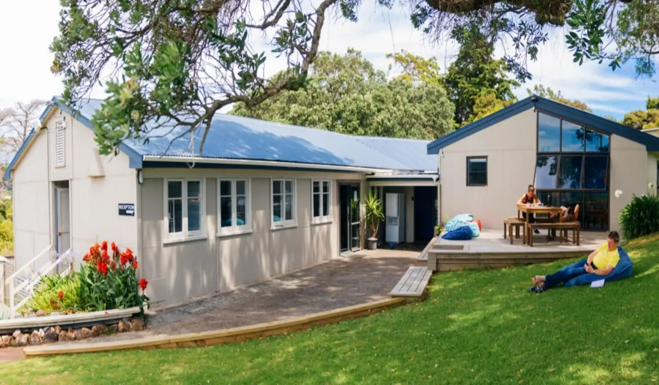 Pessoas descansando no gramado em frente ao Waiheke Backpackers Hostel em Auckland, Nova Zelândia