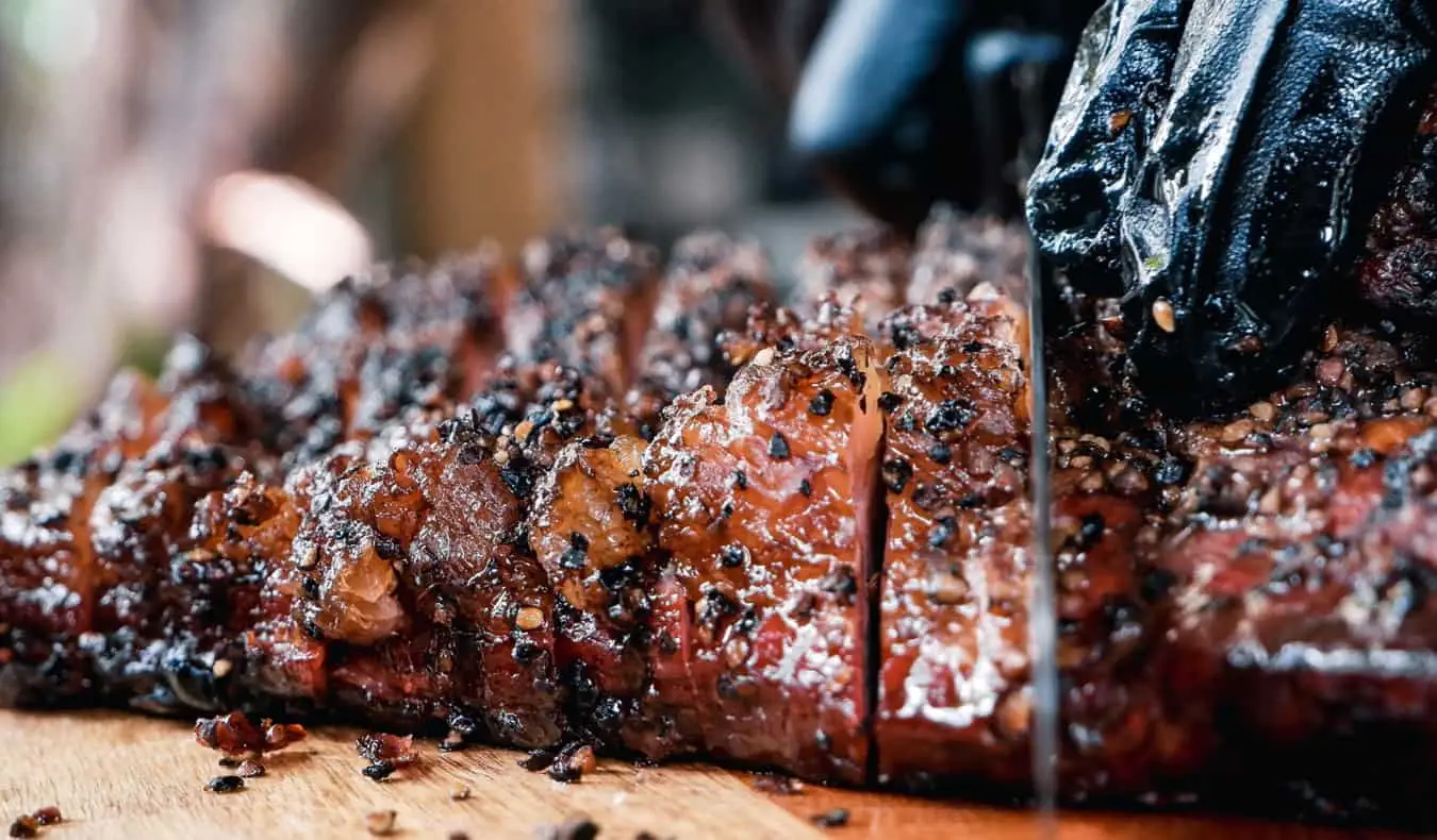 Seorang tukang masak memotong brisket BBQ di sebuah restoran