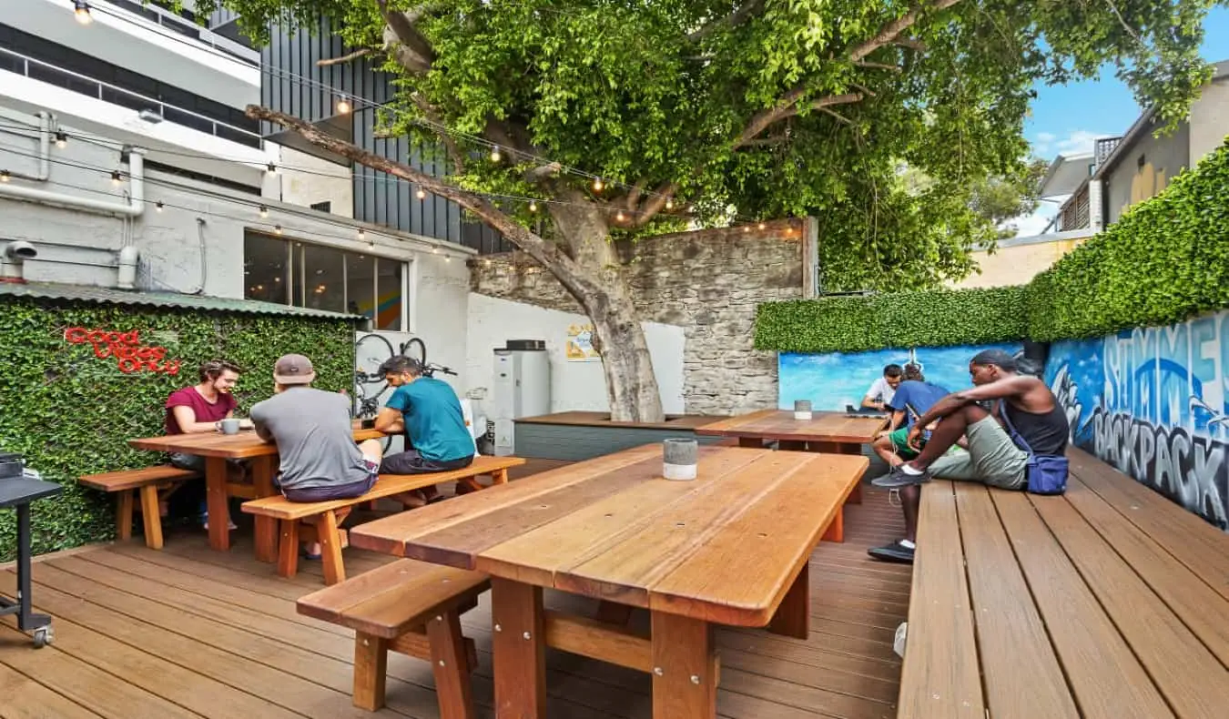 Patio exterior con mesas de picnic y bancos de madera en Summer House Backpackers Hostel en Sydney