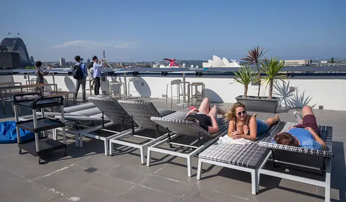 Tagterrasse med folk, der solbader på liggestole på Sydney Harbour YHA hostel i Sydney, Australien