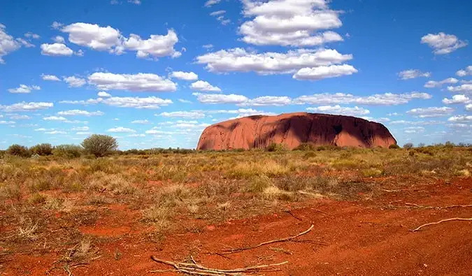 Uluru dikelilingi gurun di Australia pada hari musim panas yang cerah