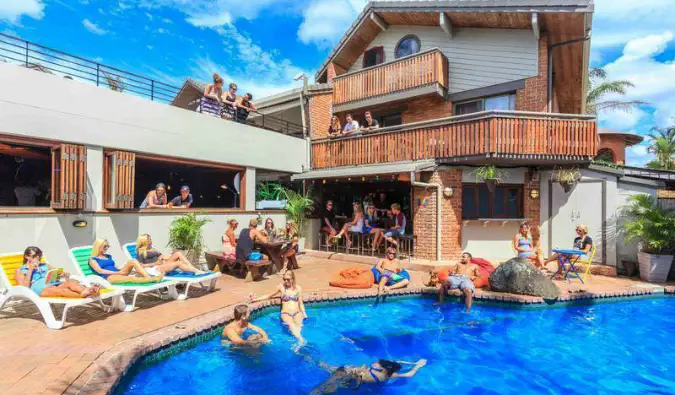 Gente nadando y descansando junto a la piscina de Aquarius Backpackers en Byron Bay, Australia.